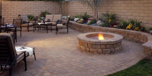 Well Landscaped courtyard with custom stonework, lush flower bed and fire pit to create a patio oasis.